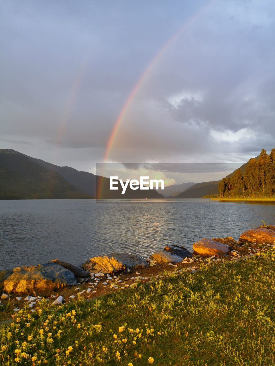 SCENIC VIEW OF RAINBOW OVER LAKE AND MOUNTAINS