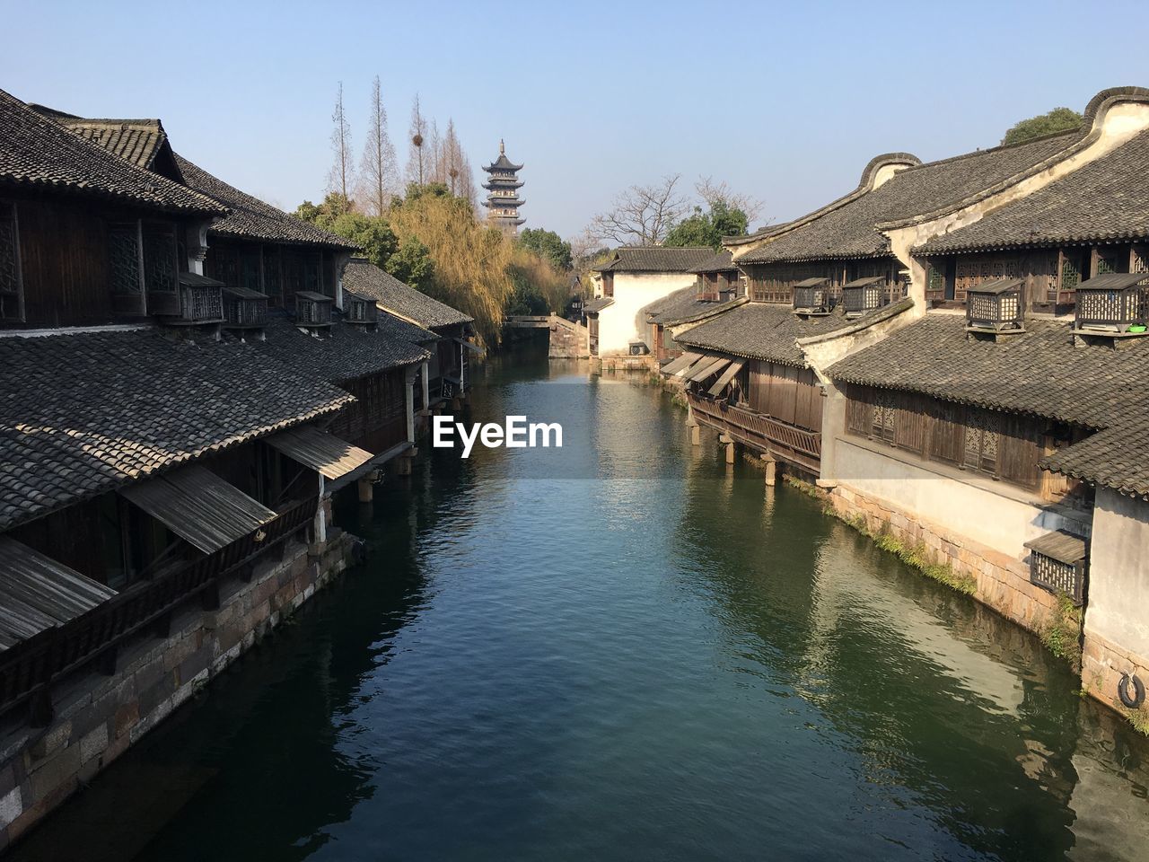 View of buildings by river against sky