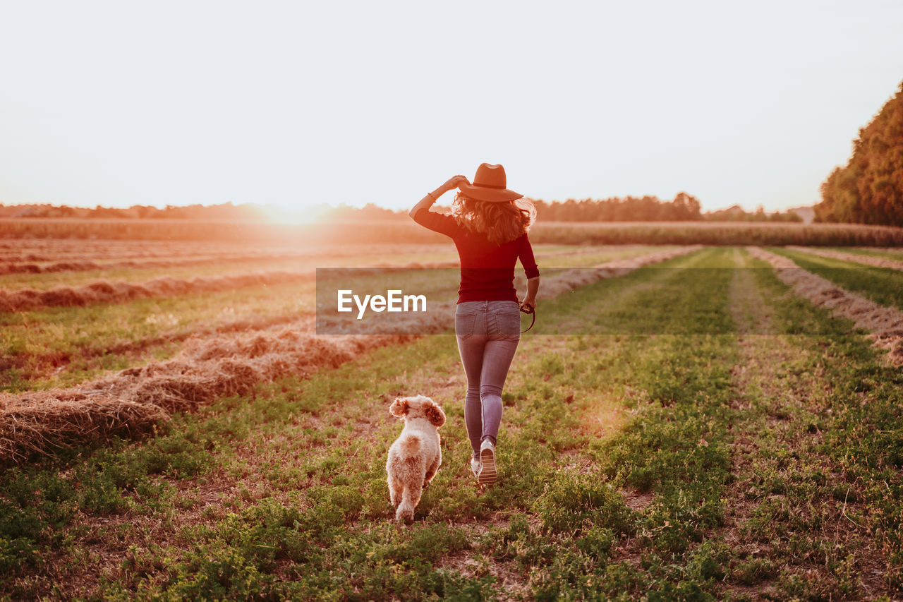 Rear view of woman running with dog on land