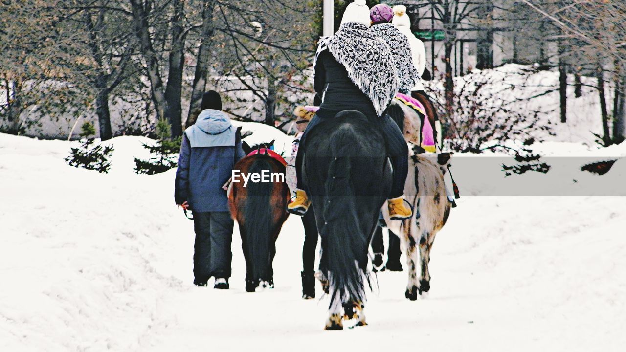 REAR VIEW OF MAN RIDING ON SNOW FIELD