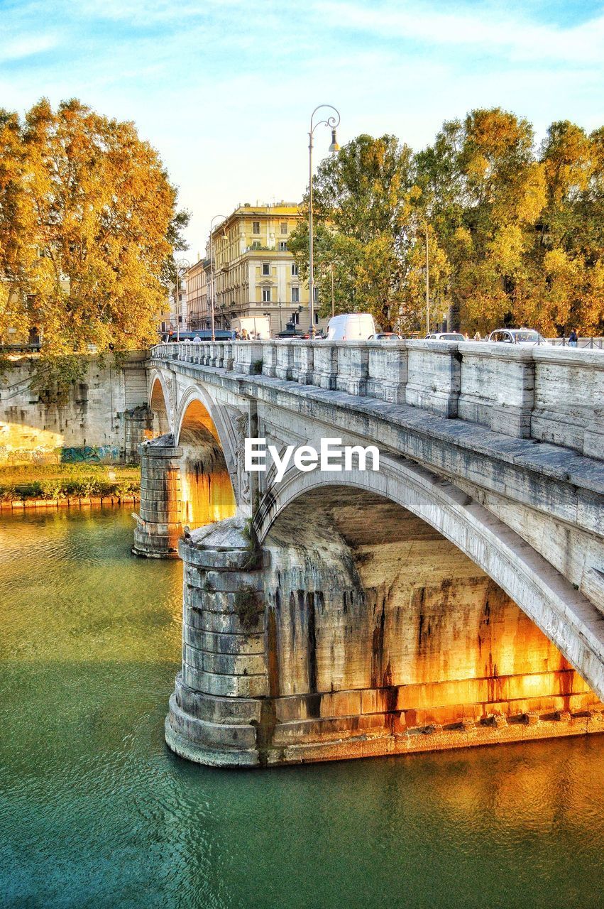 Arch bridge over river against sky during autumn