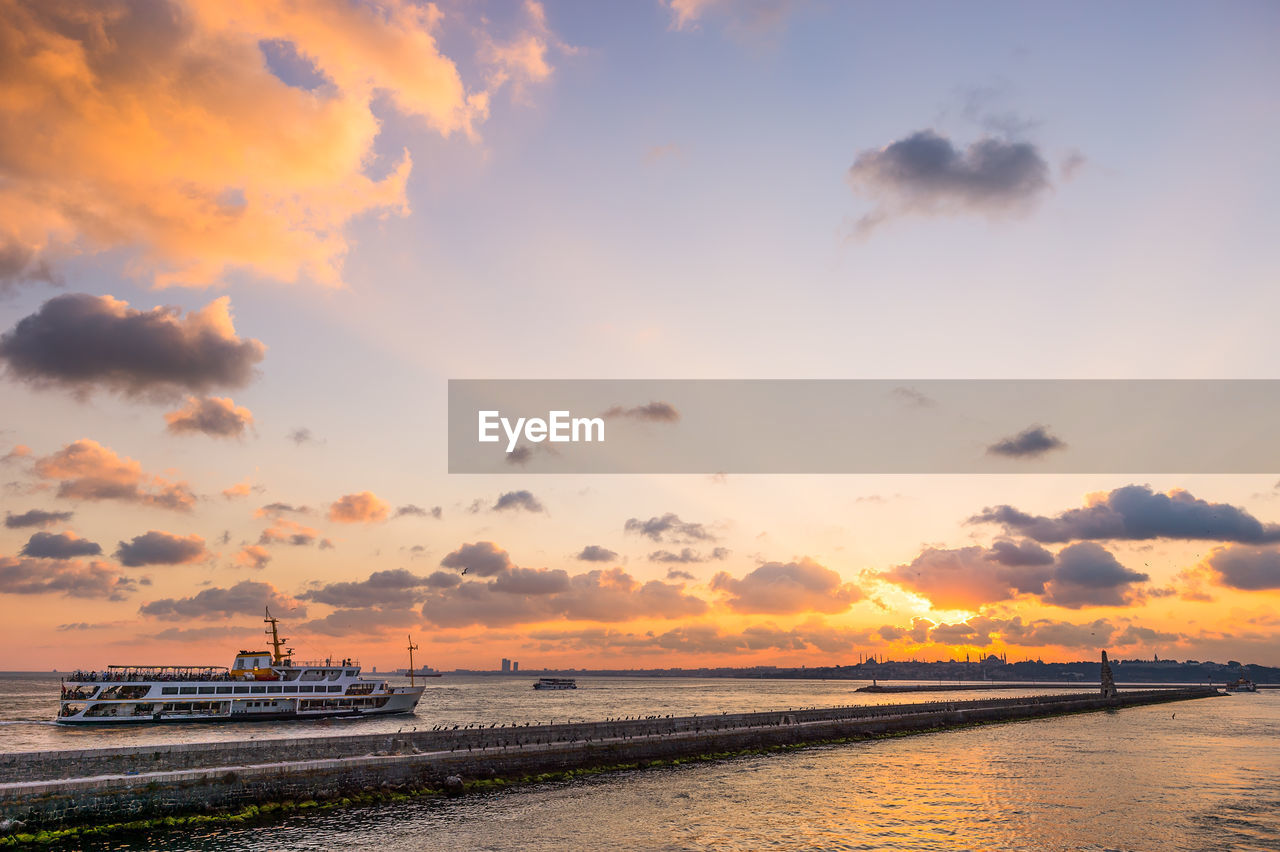 Ferry boat sailing in sea against sky during sunset