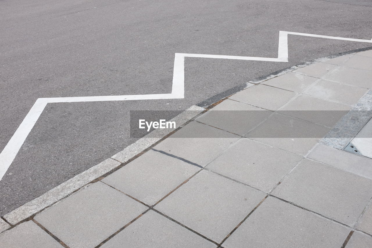 High angle view of road marking on city street by sidewalk