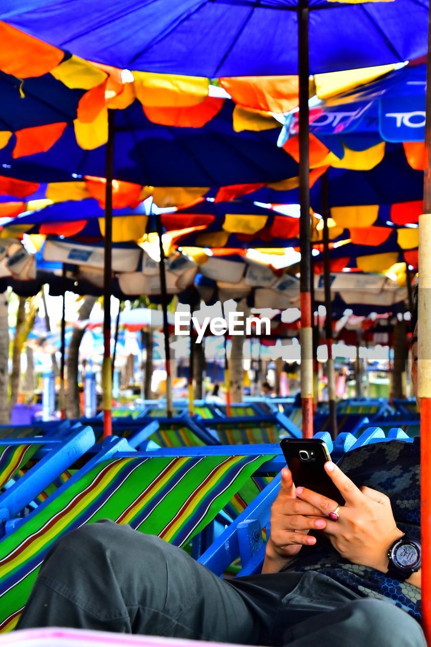 LOW SECTION OF MAN HOLDING MULTI COLORED UMBRELLAS