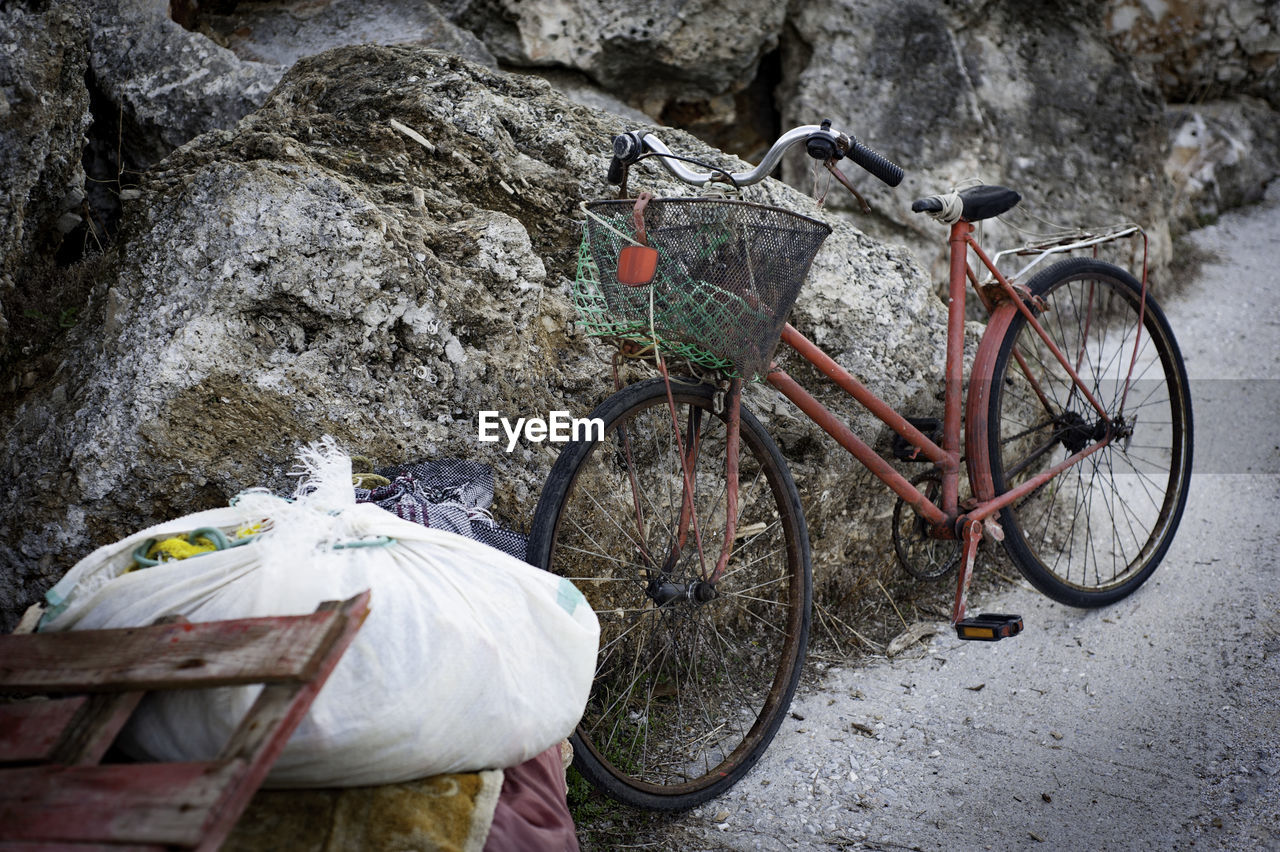 Bicycle parked on street against rock