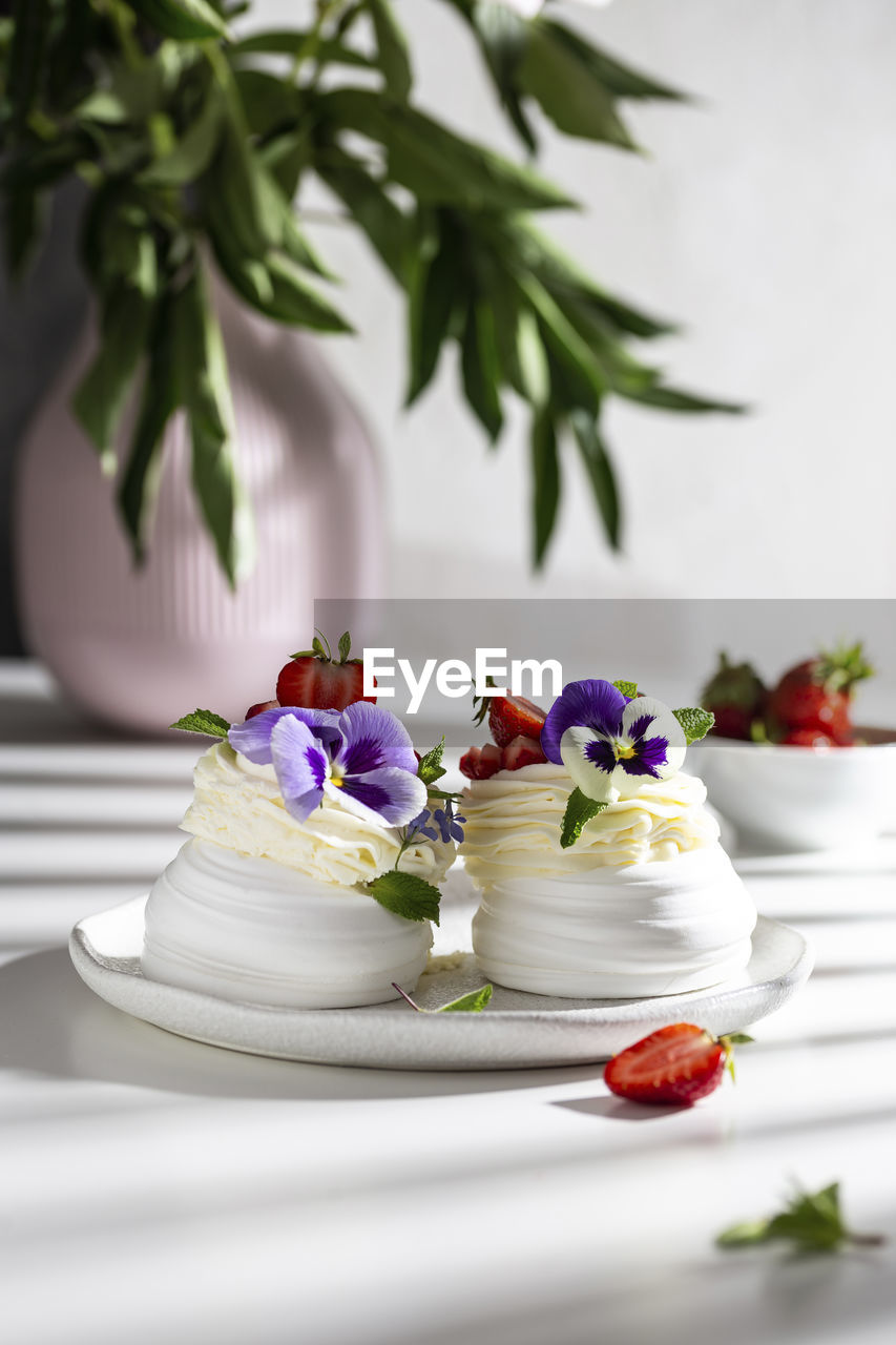 Sweet pavlova's dessert decorated with fresh strawberry and flowers