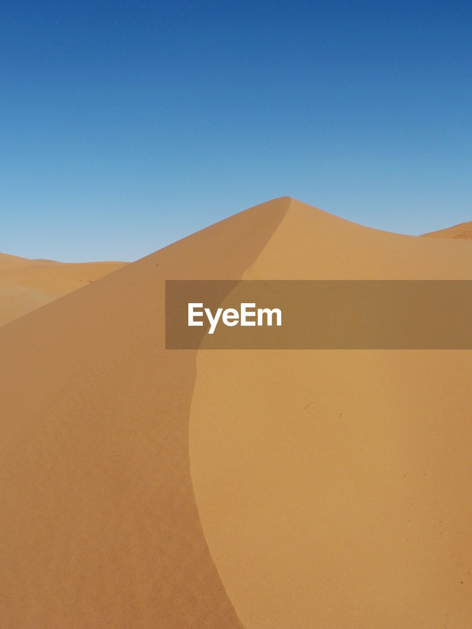 Low angle view of sand dunes against blue sky