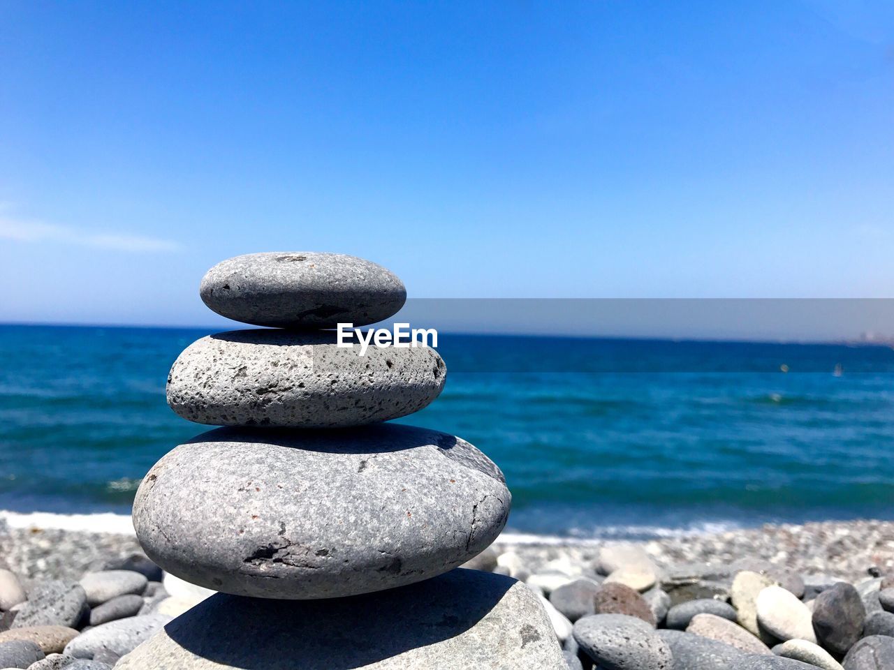 Close-up of stack of pebbles on beach against sky