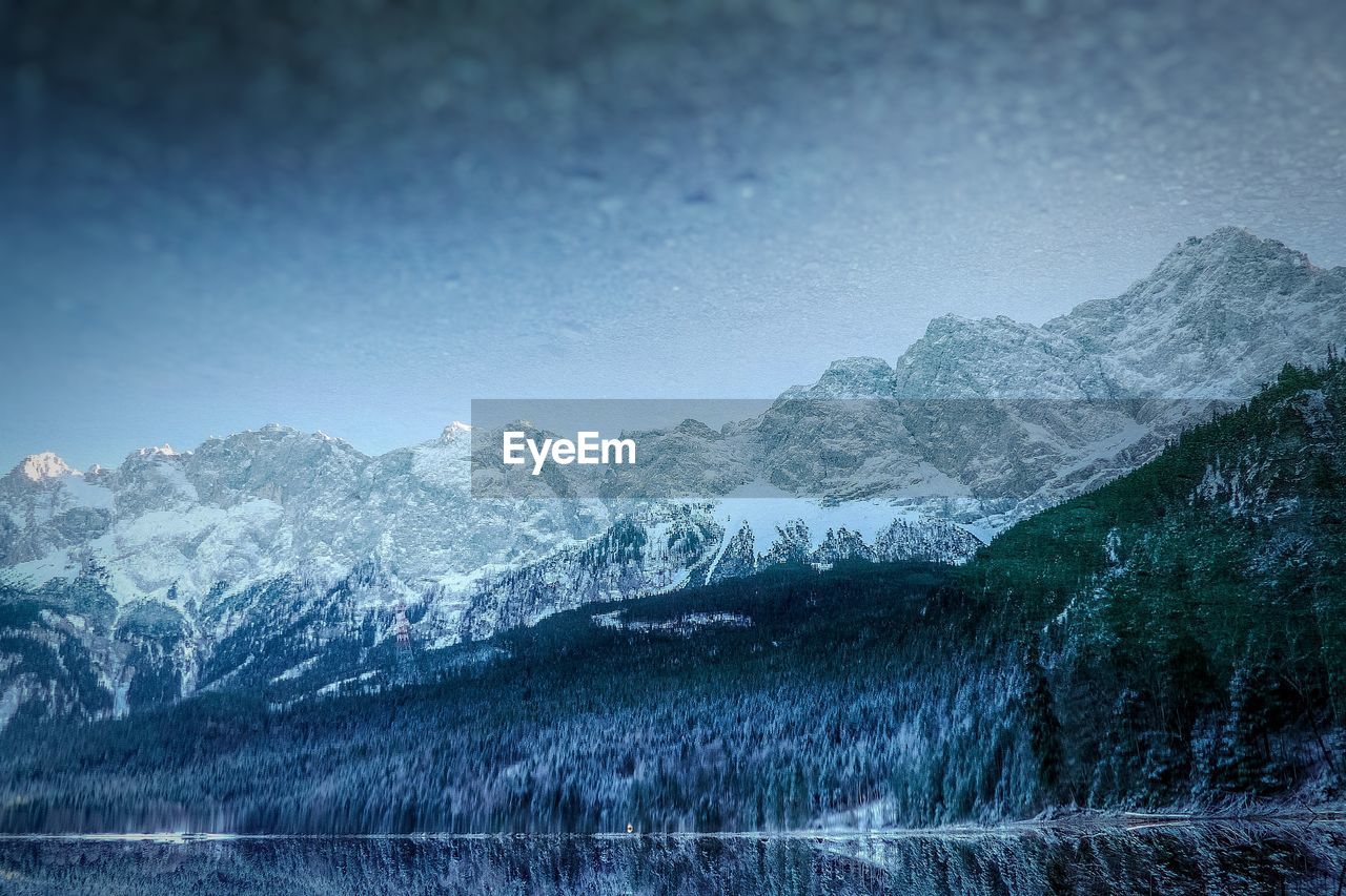 Scenic view of lake by snowcapped mountains against sky