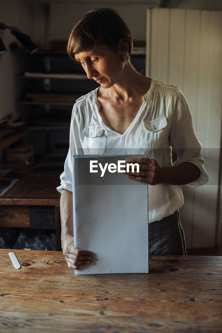 Woman handling stack of paper sheets, handmade book production process