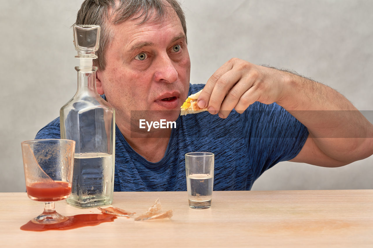 PORTRAIT OF A MAN DRINKING GLASS ON TABLE AT RESTAURANT