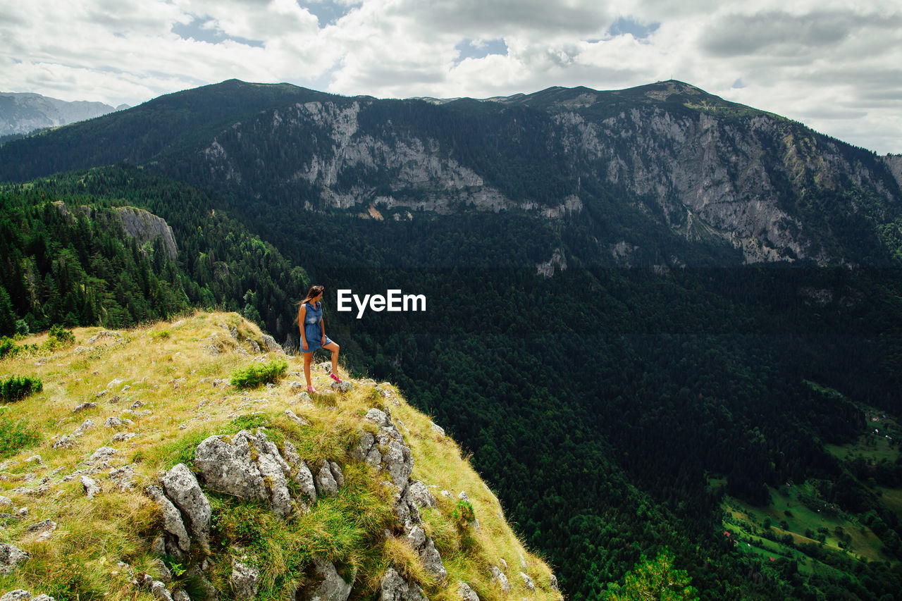 Woman on green mountains against sky