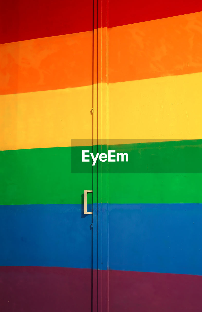 Full frame wall with door colored in bright colors of rainbow spectrum for pride concept