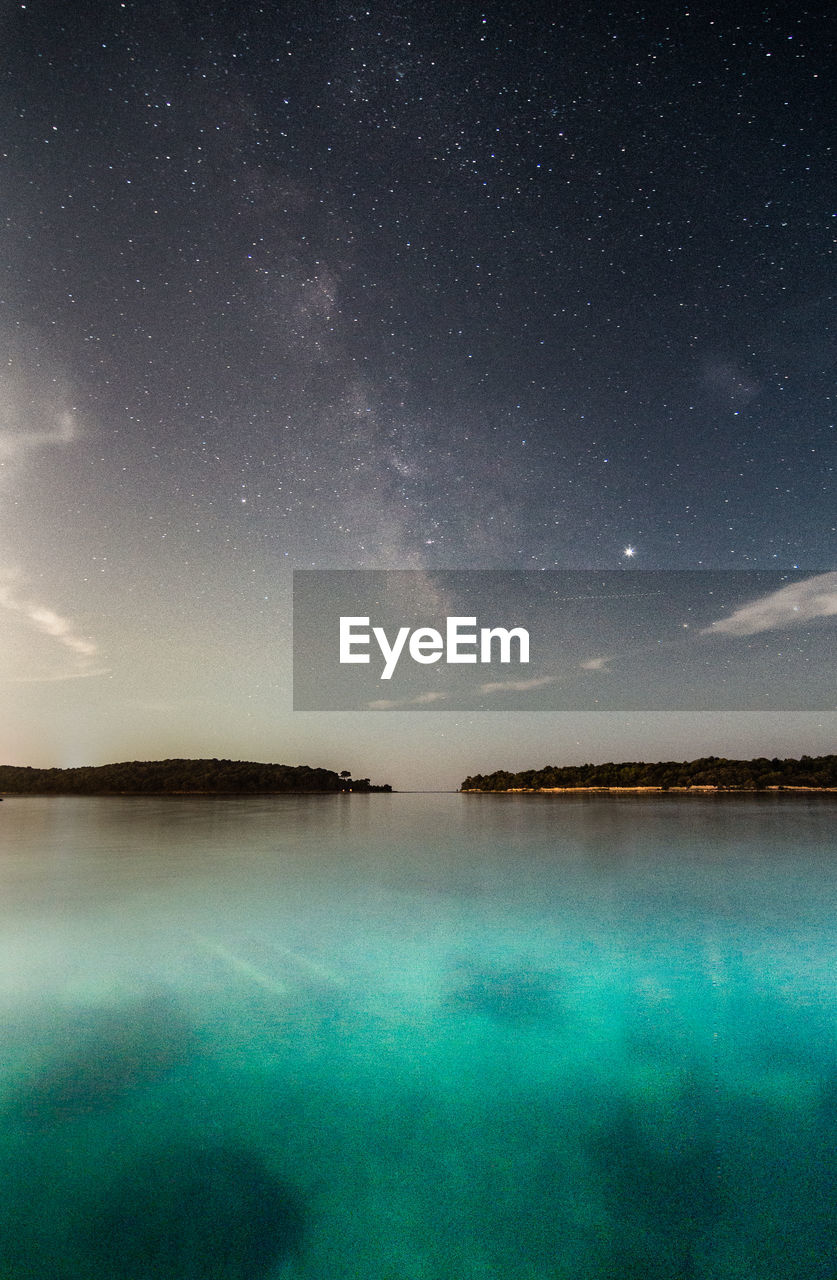 Scenic view of lake against sky at night