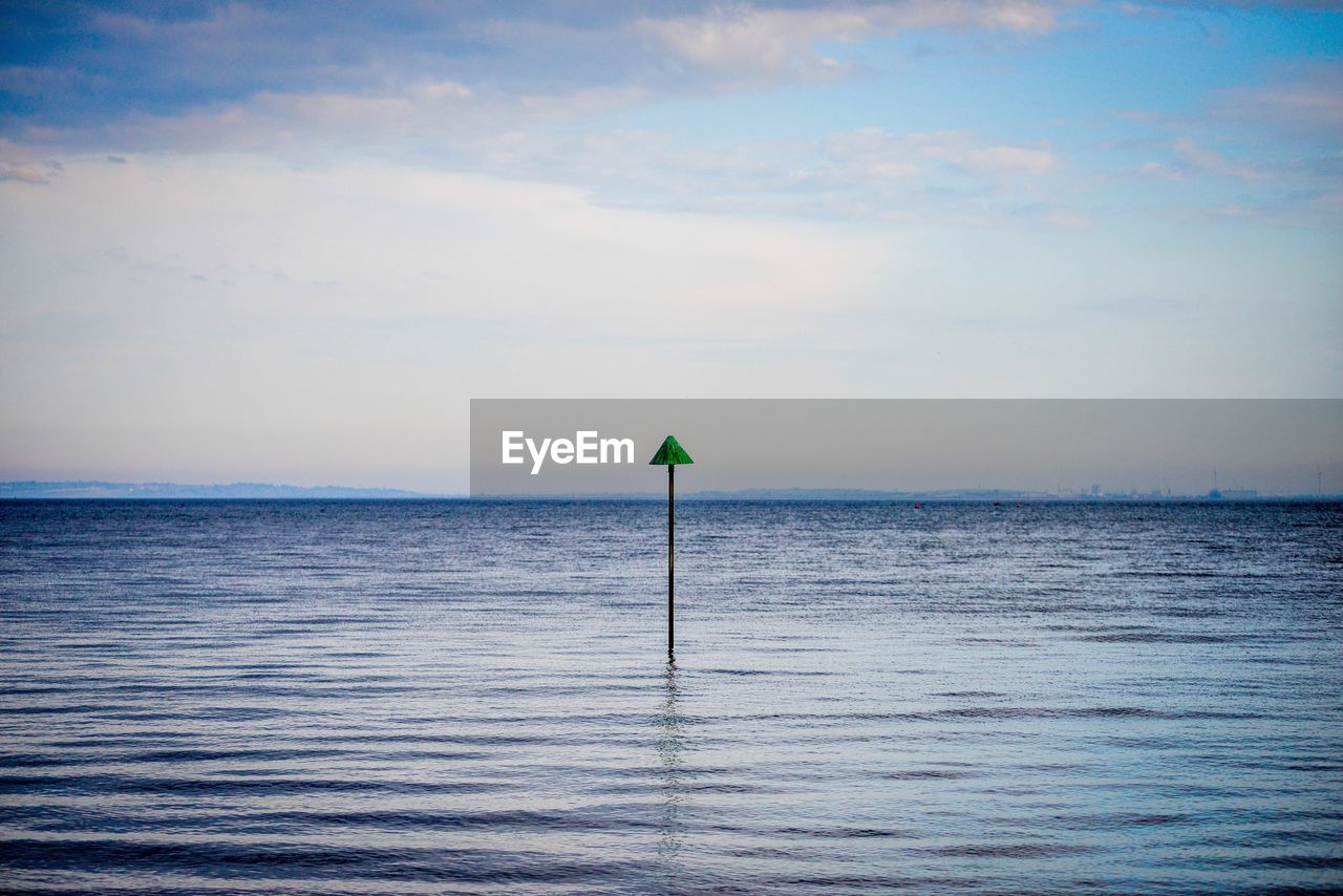 Pole in sea against sky