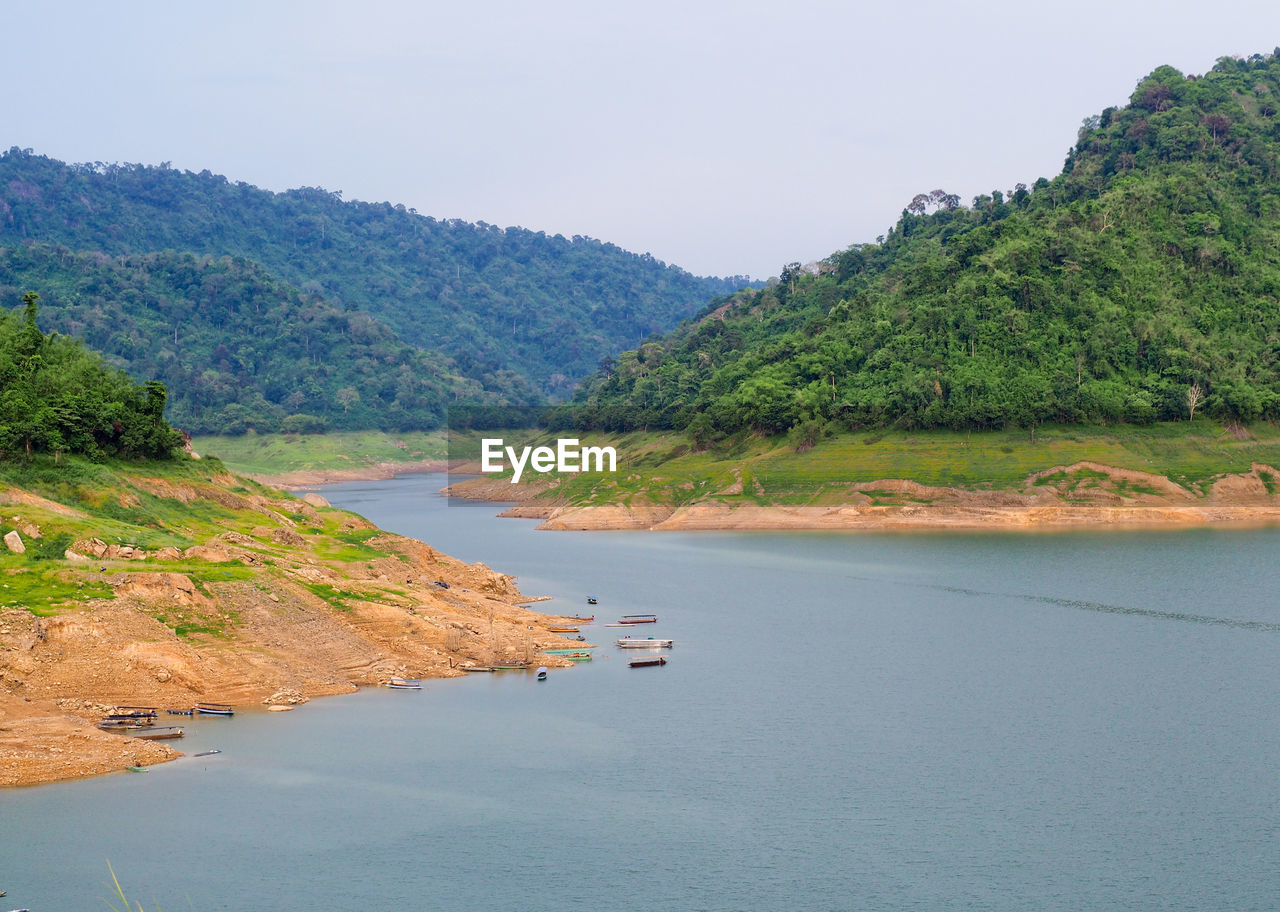 Scenic view of river by mountains against sky