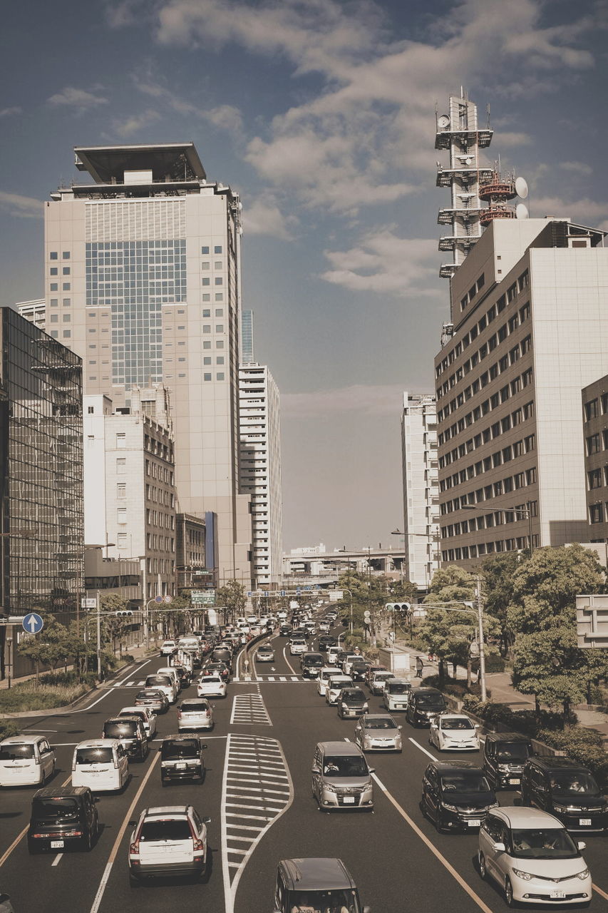 Cars on road by buildings against sky