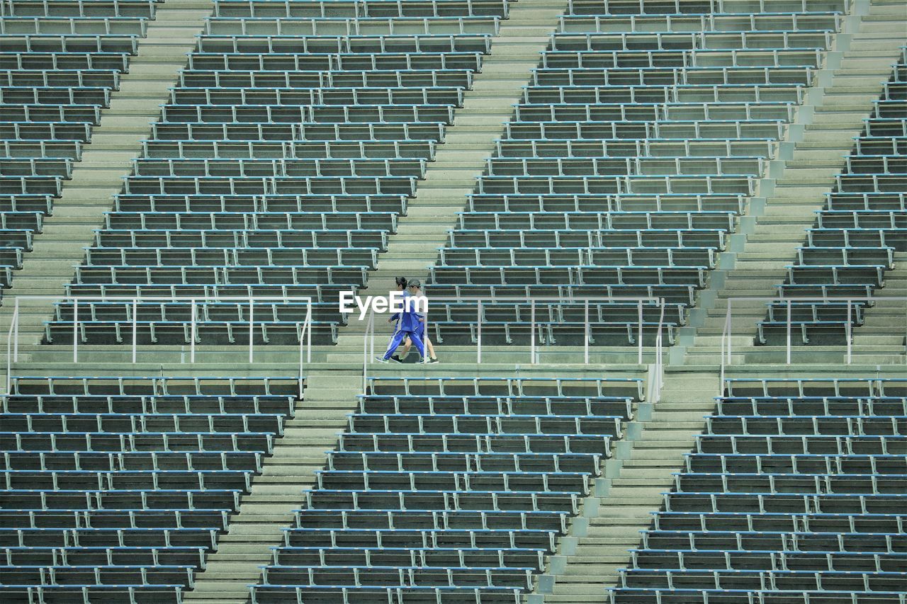 High angle view of 2 young people walking in empty stadium
