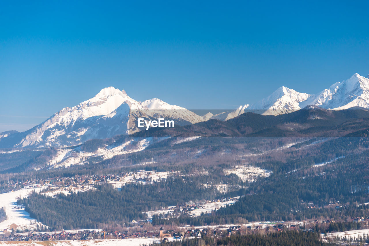 Scenic view of snowcapped mountains against clear blue sky