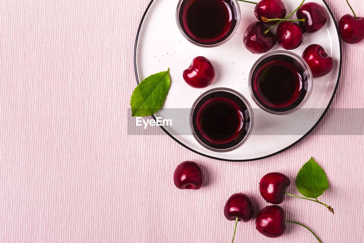 Cherry alcohol drink liquor or brandy on a pink background