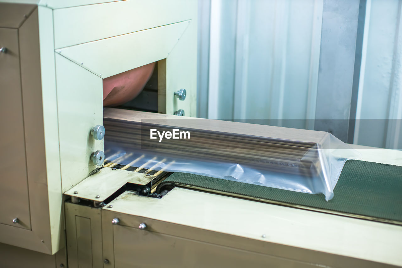 Wood flooring planks being covered in plastic protection with factory machine