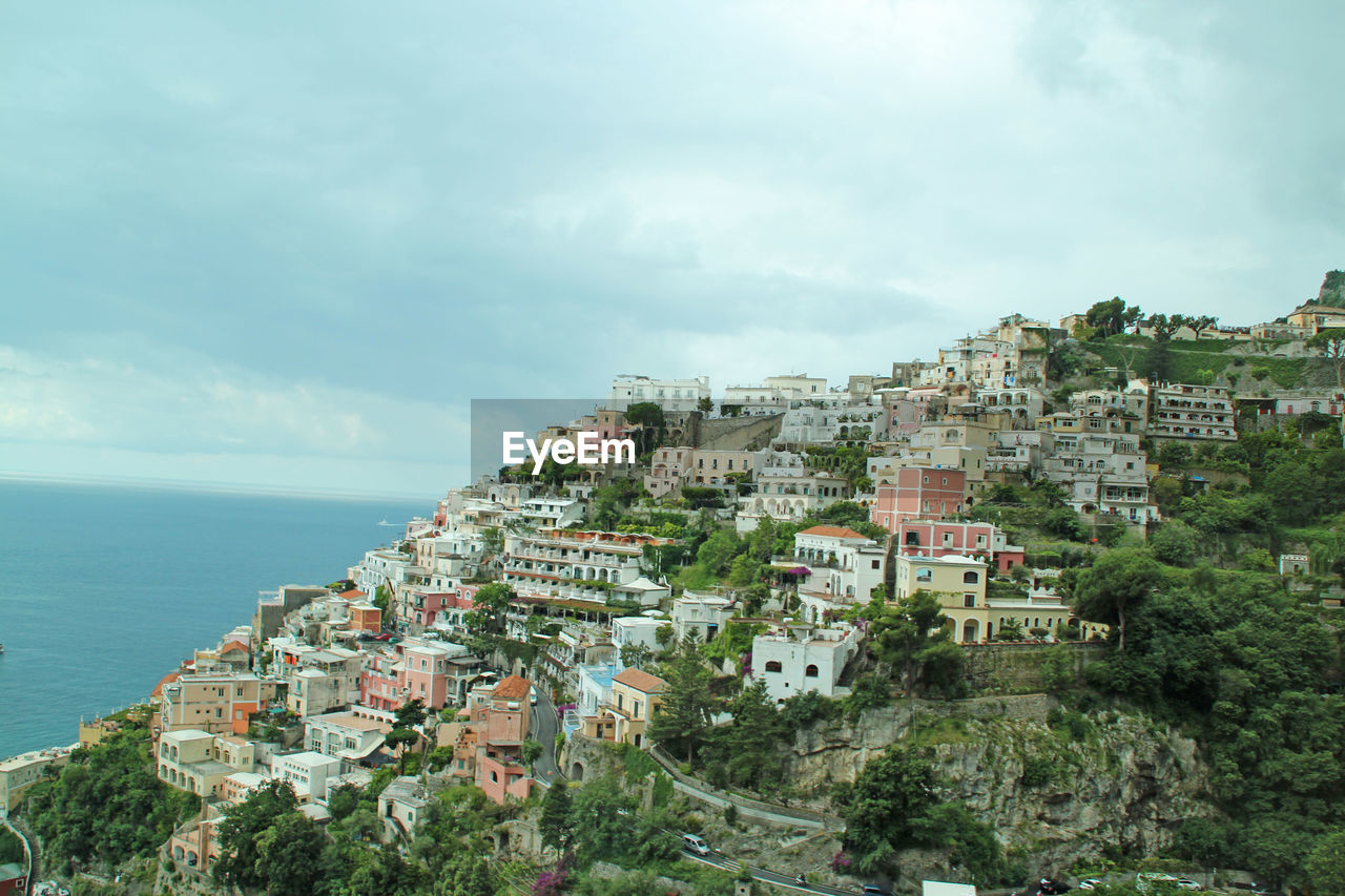 Positano on mountain by tyrrhenian sea against cloudy sky