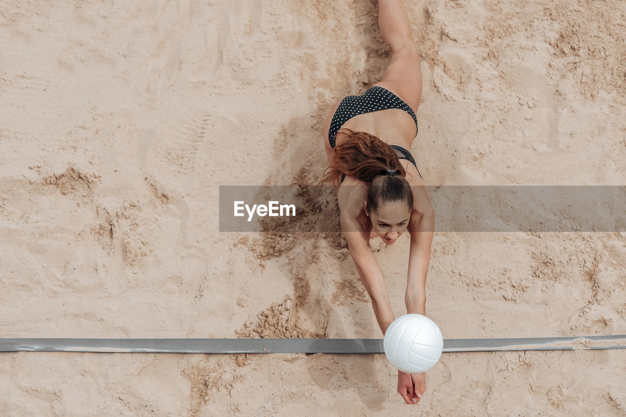 High angle view of woman playing volleyball on sand at beach