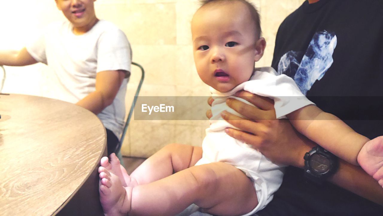 CLOSE-UP OF FATHER AND SON PLAYING WITH BABY