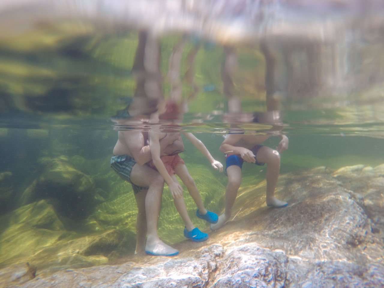Legs of three people standing in water