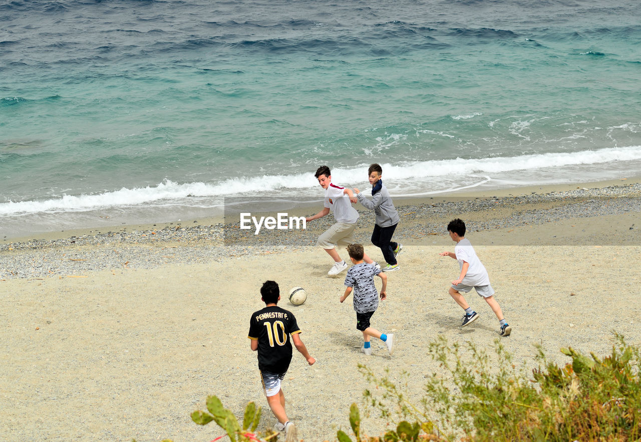 HIGH ANGLE VIEW OF SIBLINGS PLAYING ON BEACH