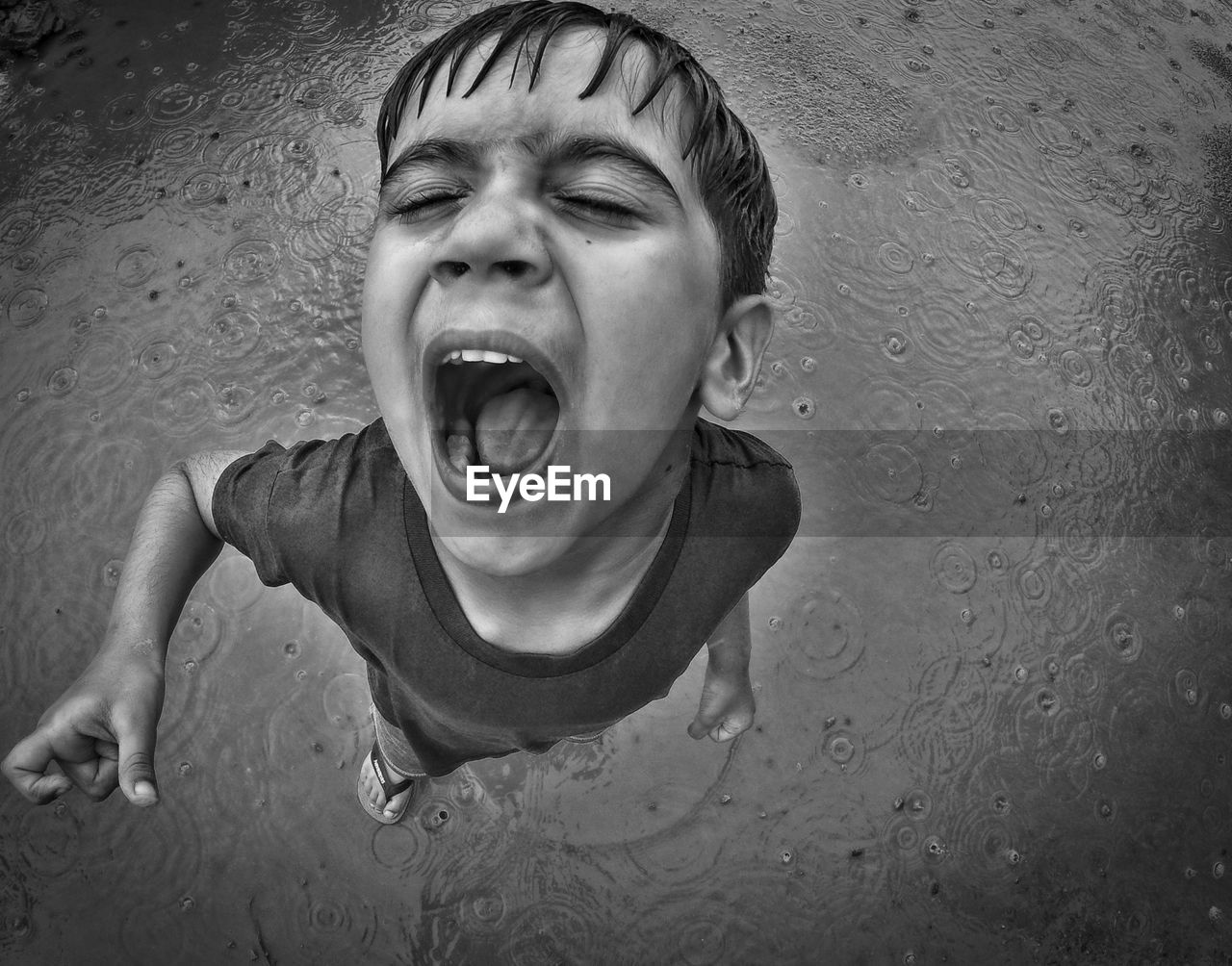 Overhead view of a child with mouth open in the rain