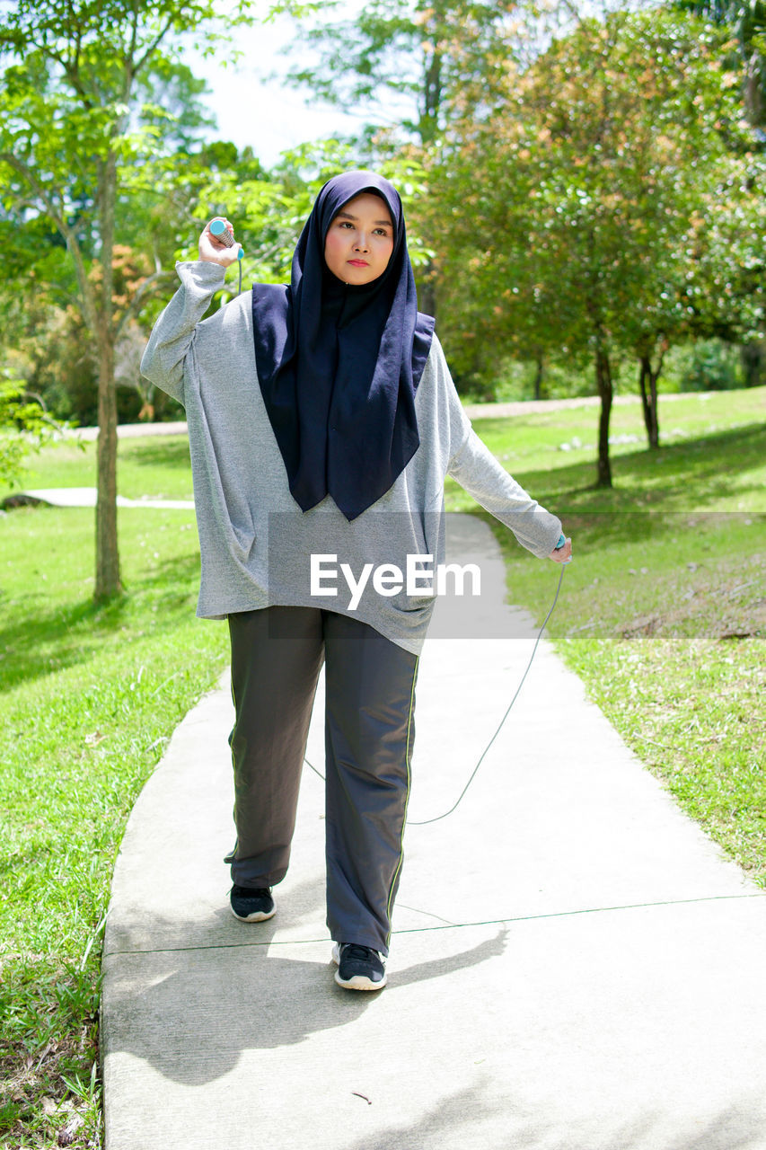 PORTRAIT OF BEAUTIFUL WOMAN STANDING ON FOOTPATH