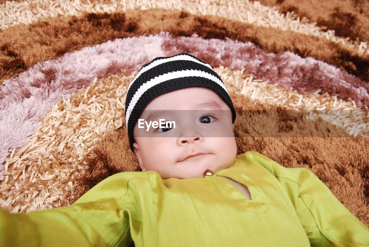 PORTRAIT OF CUTE BABY GIRL LYING ON SOFA AT HOME