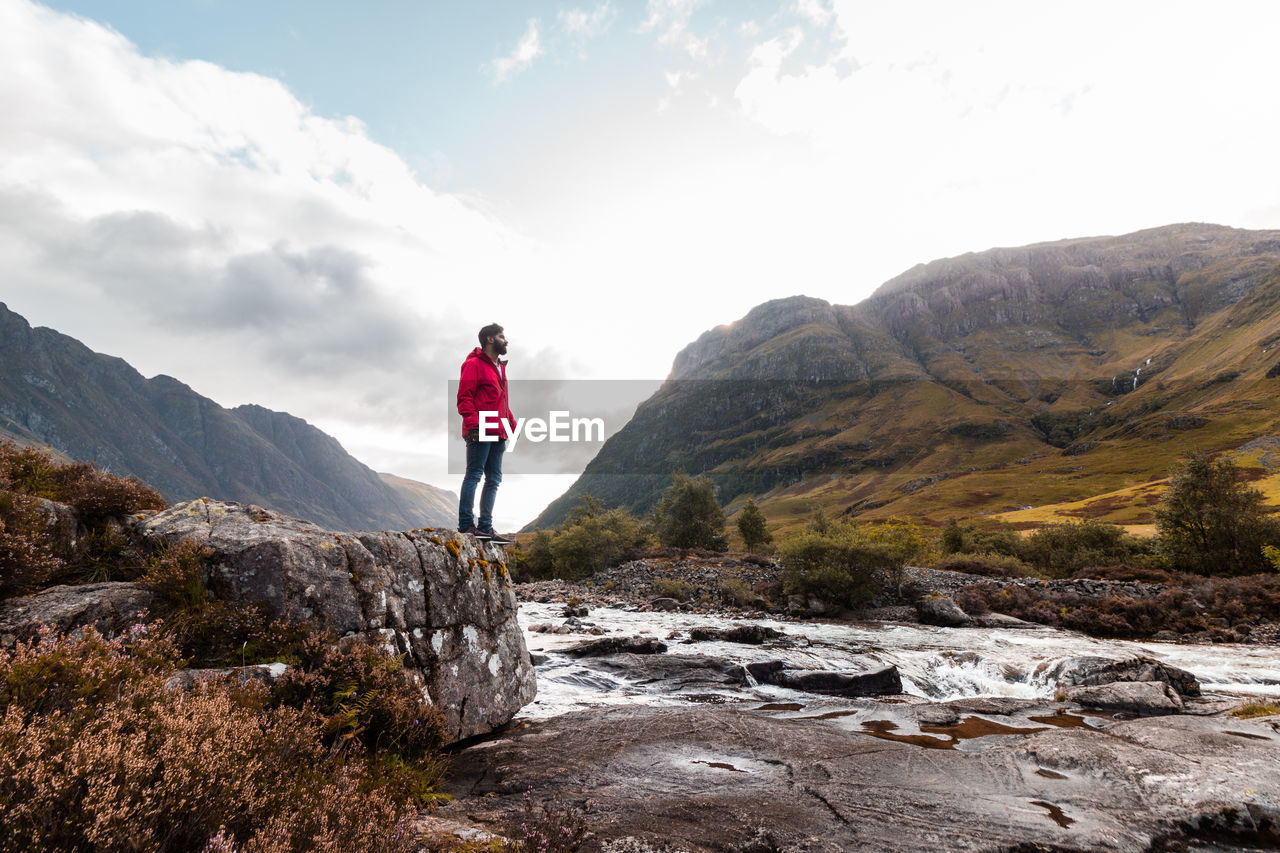 Low angle view of man standing on rock against sky