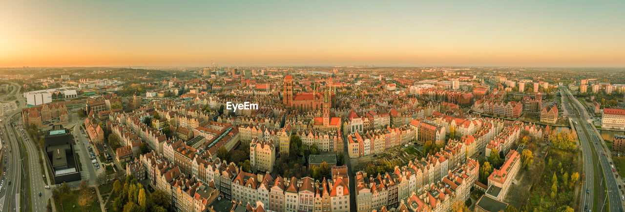 HIGH ANGLE VIEW OF ILLUMINATED CITY AGAINST SKY DURING SUNSET