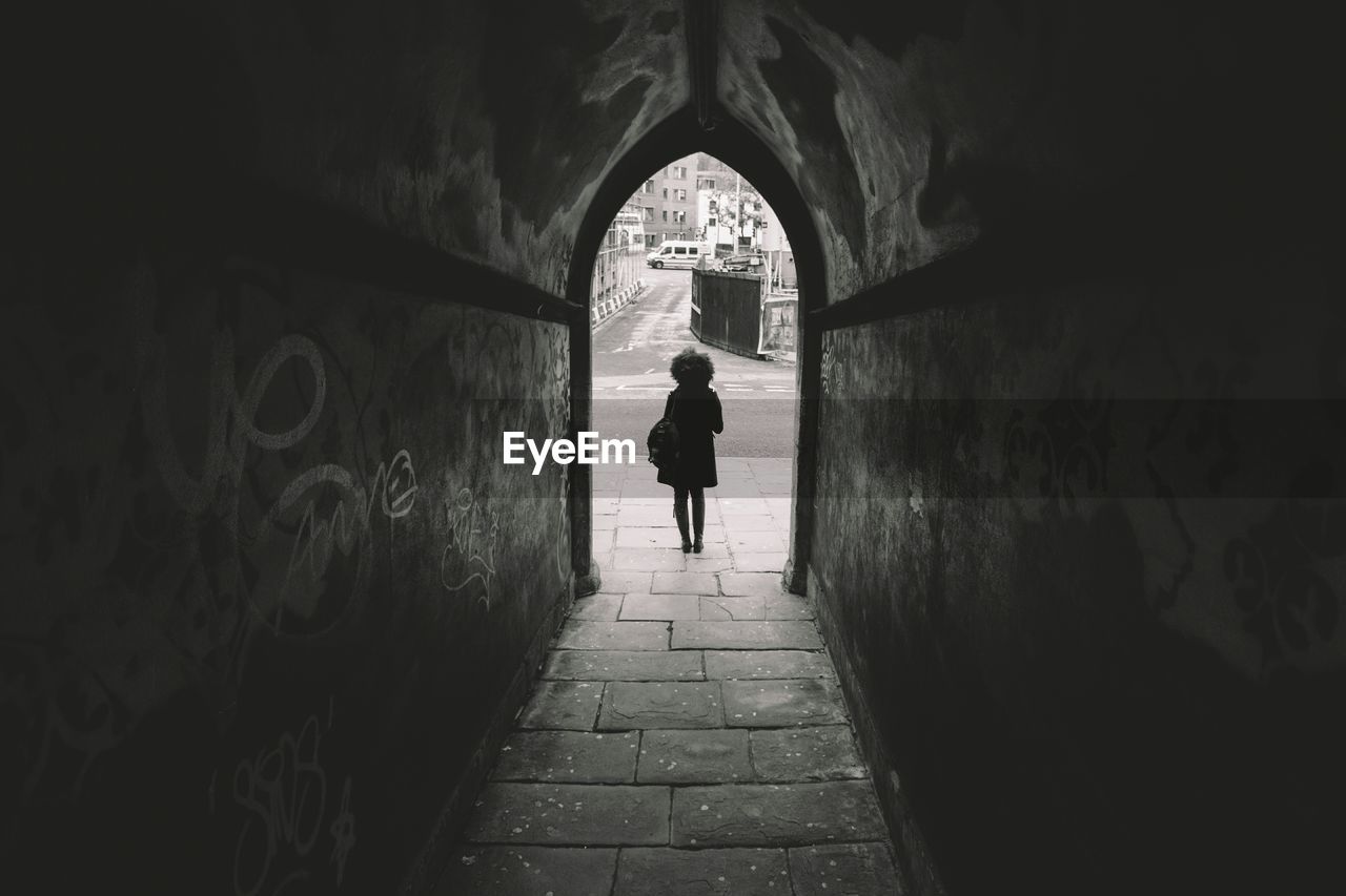 Rear view of woman standing outside archway