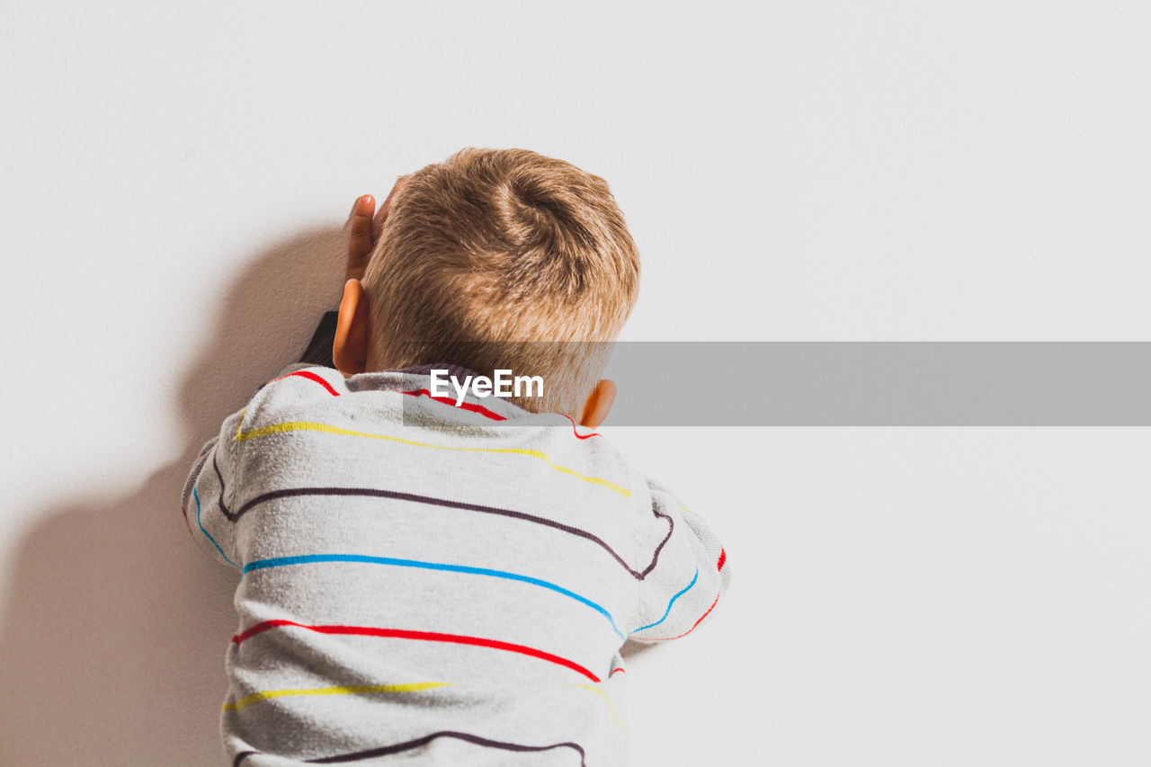 Rear view of boy against white background