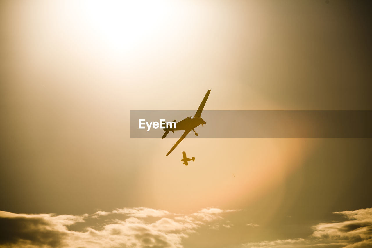 LOW ANGLE VIEW OF AIRPLANE AGAINST SKY DURING SUNSET