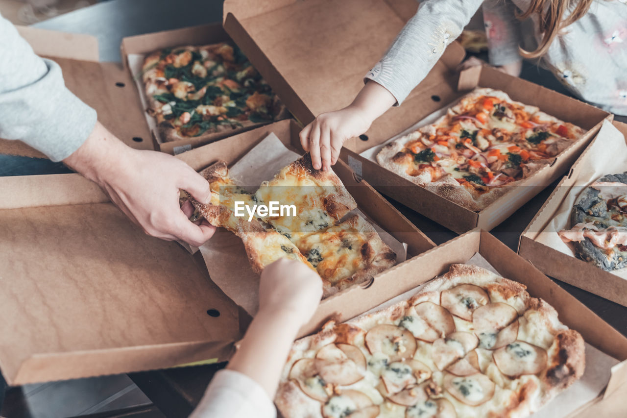 Cropped hands of people holding pizza at home