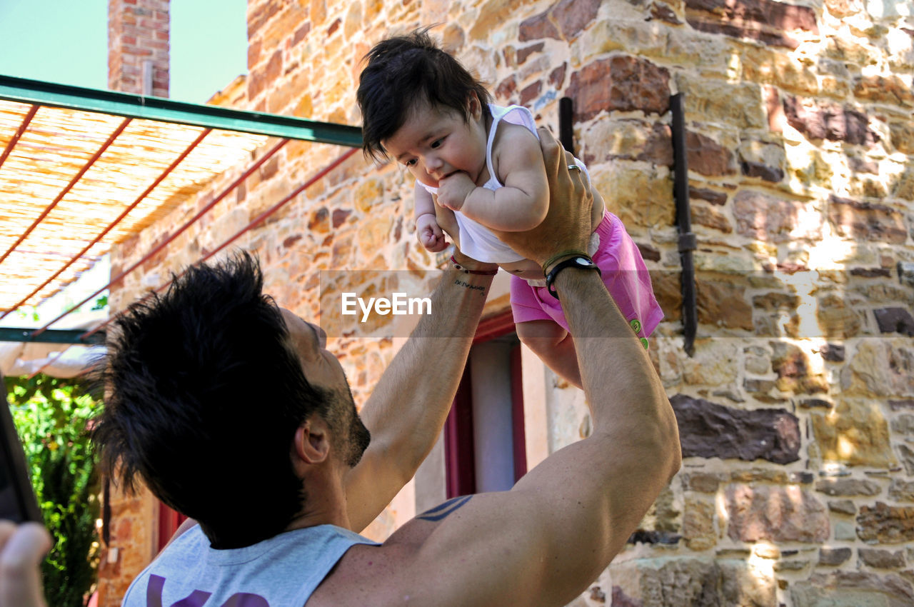 Father playing with daughter while standing in yard