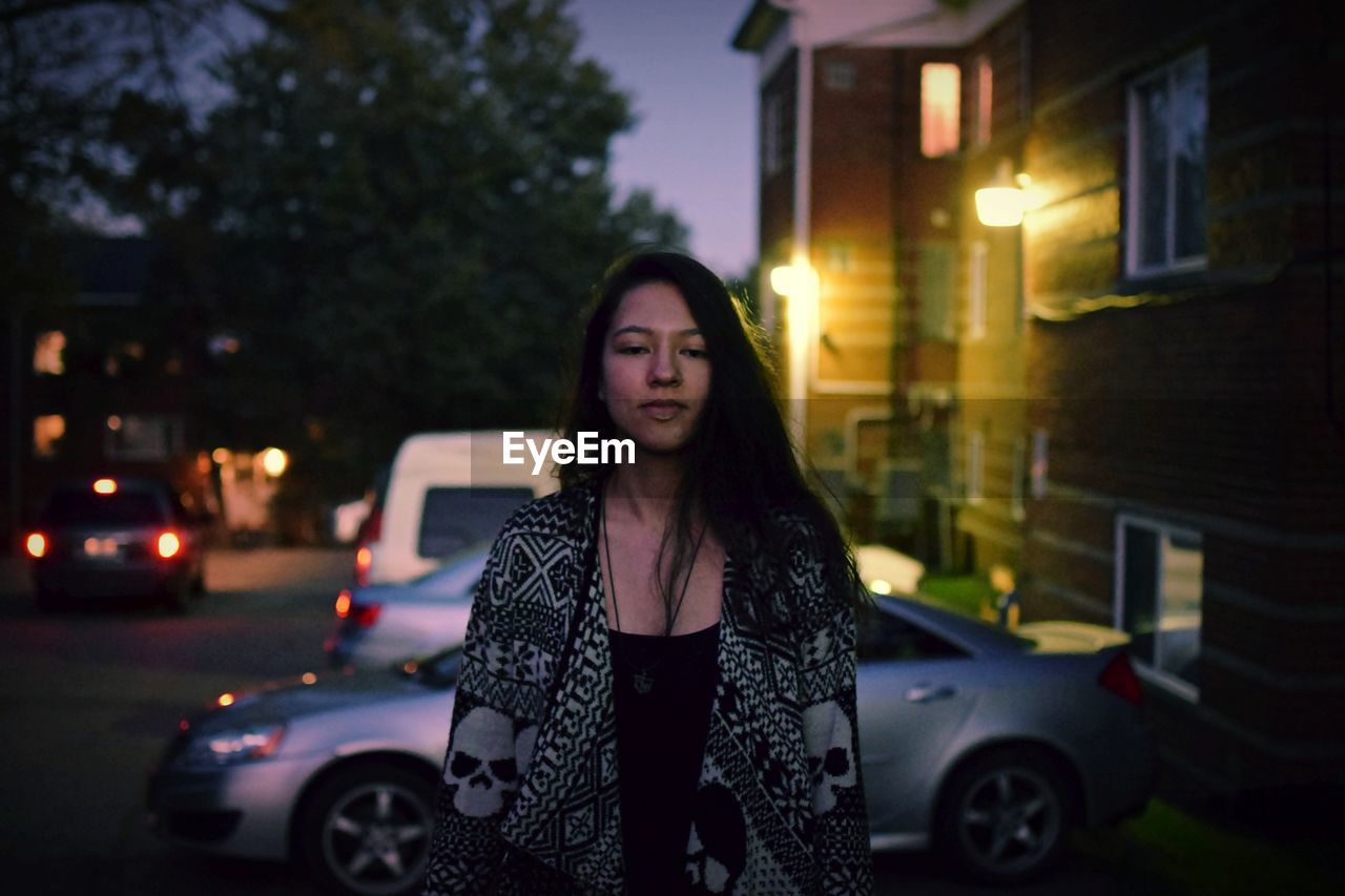 Portrait of young woman standing outdoors at night