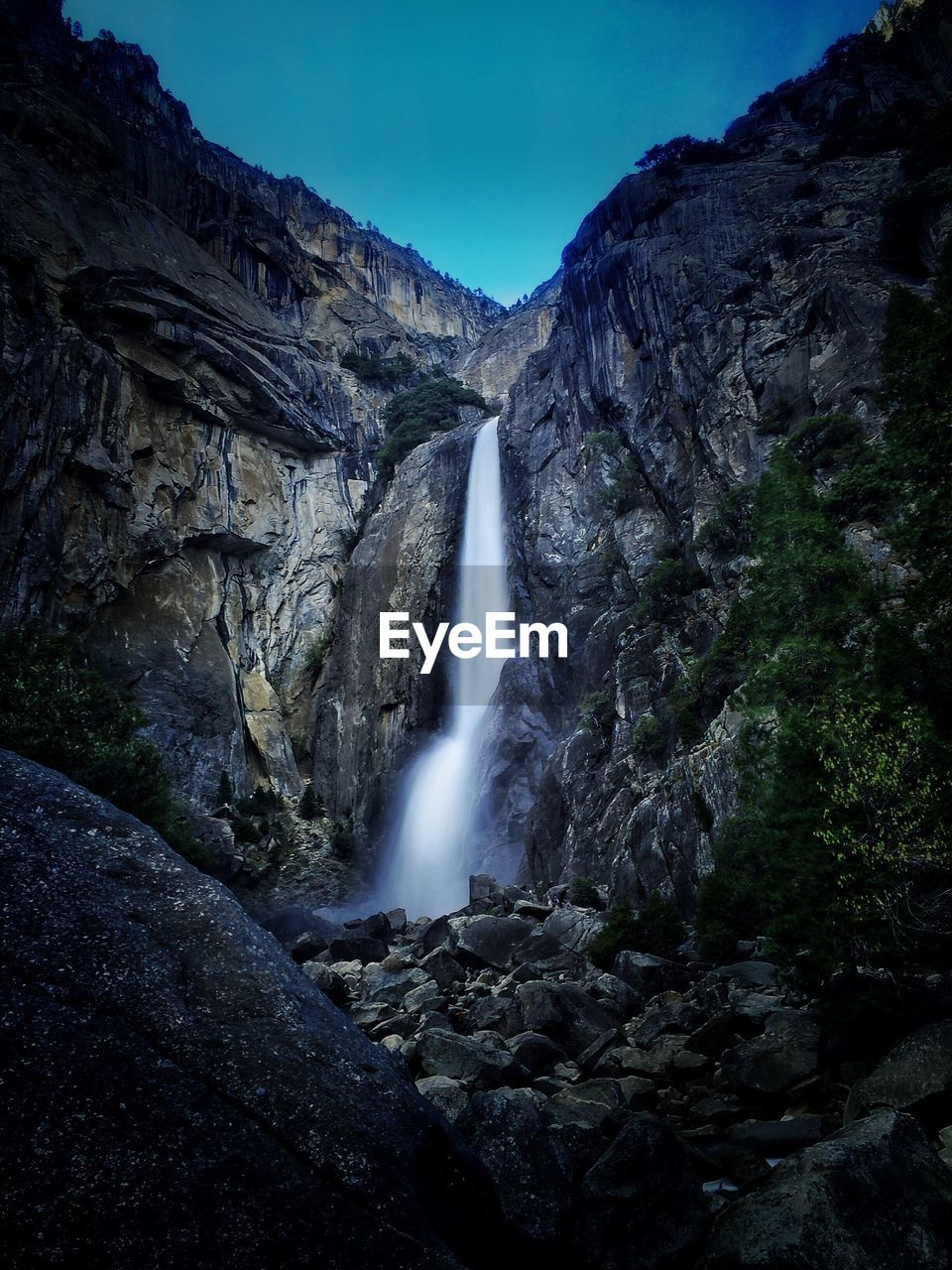 Low angle view of waterfall along rocks