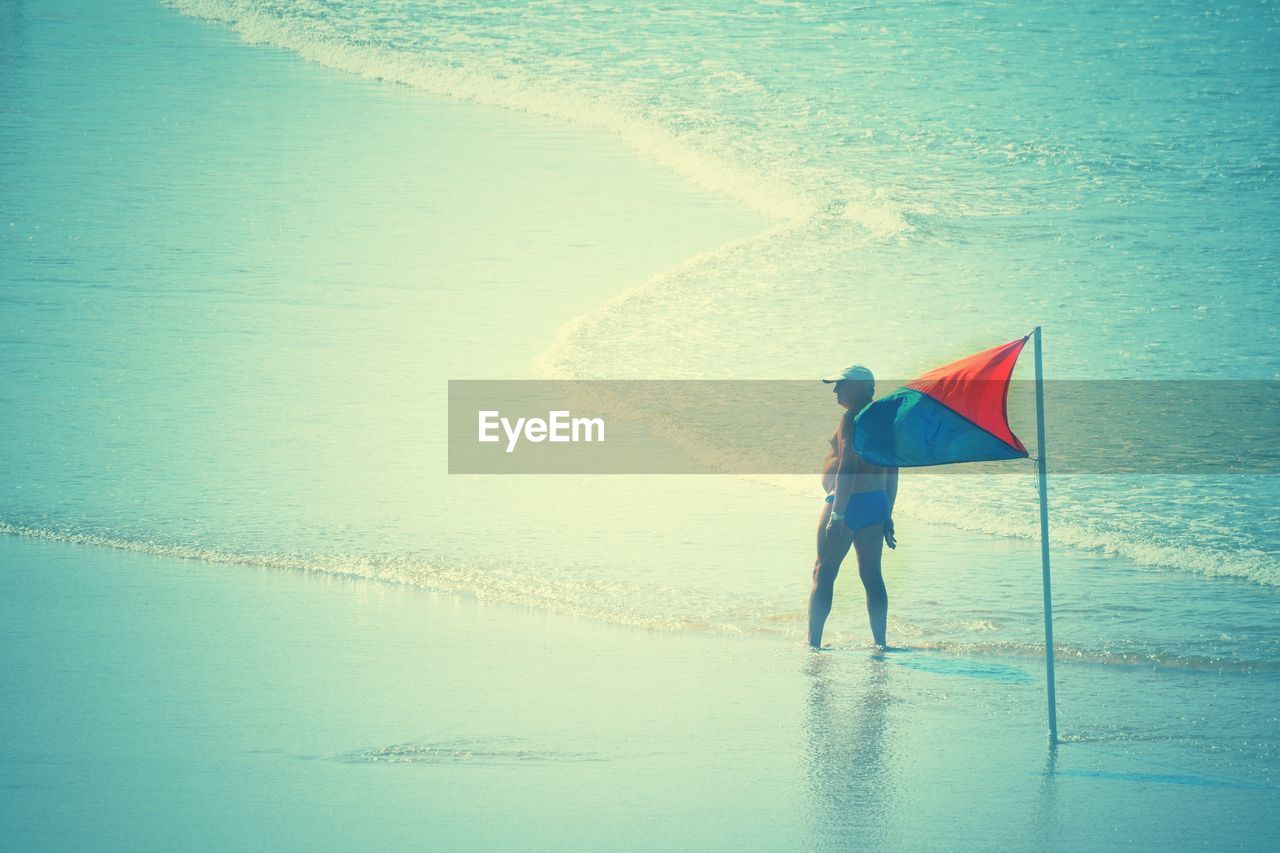 BOY STANDING ON BEACH