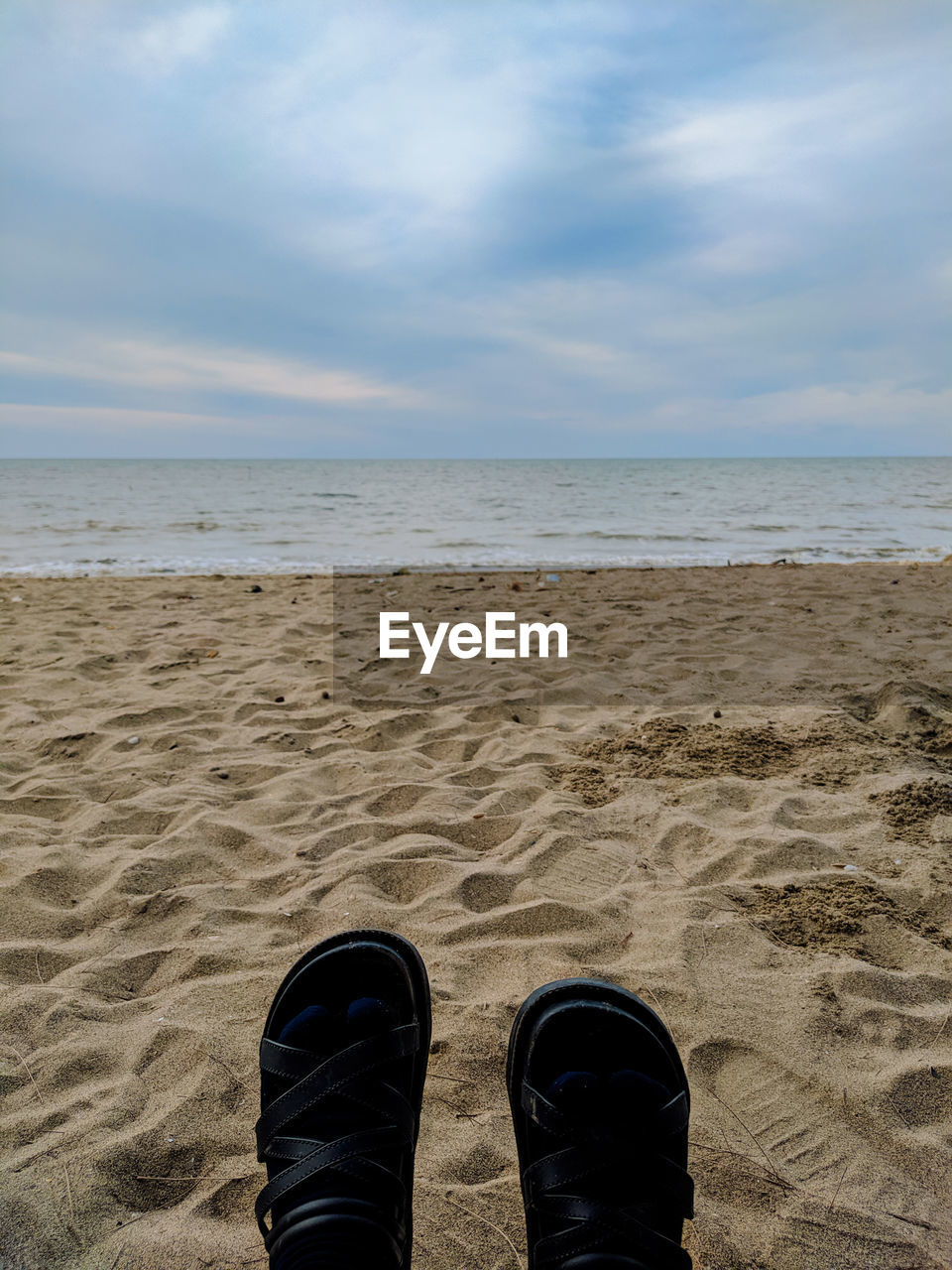 LOW SECTION OF MAN ON BEACH AGAINST SKY