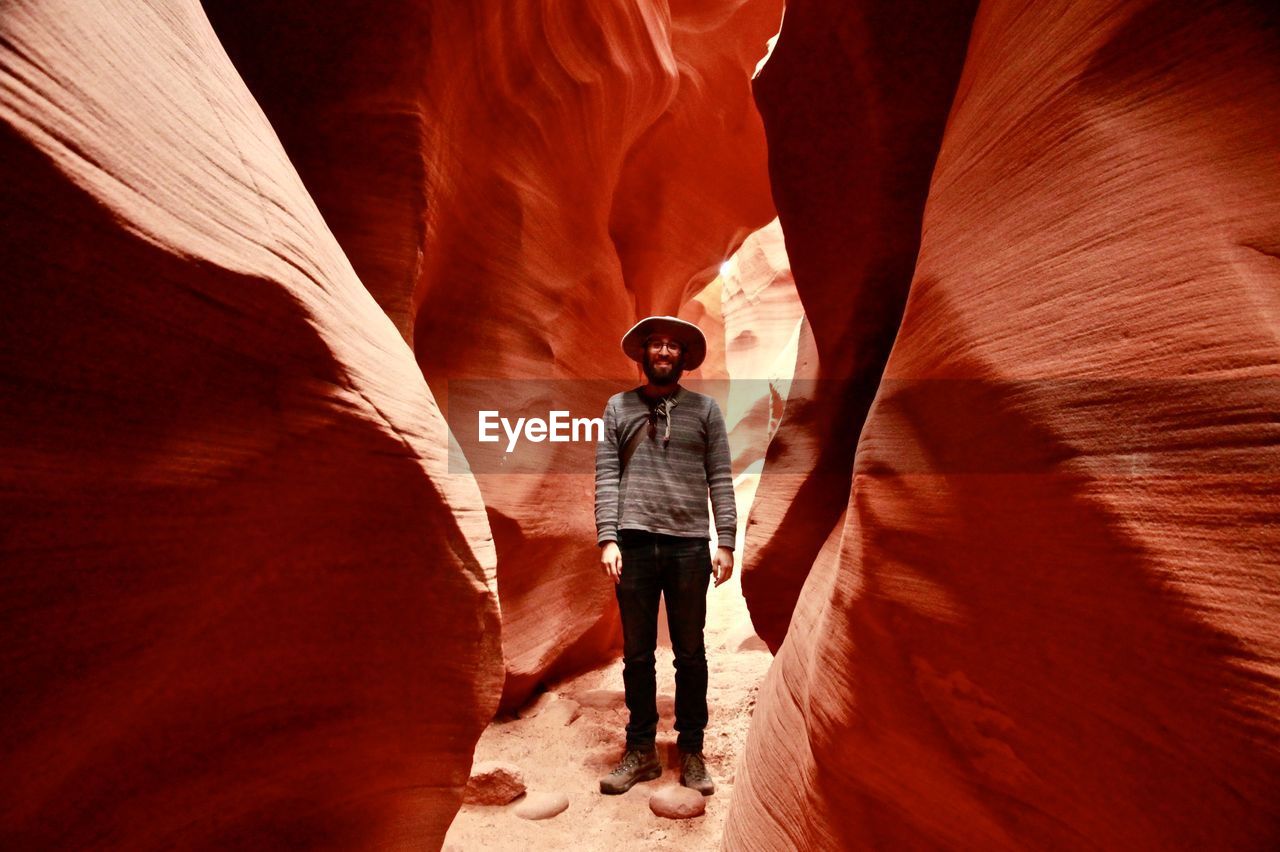 Full length portrait of man standing amidst rock formations