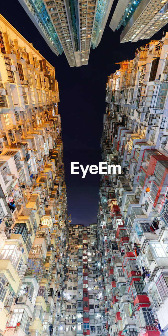 Directly below shot of illuminated buildings against sky at night