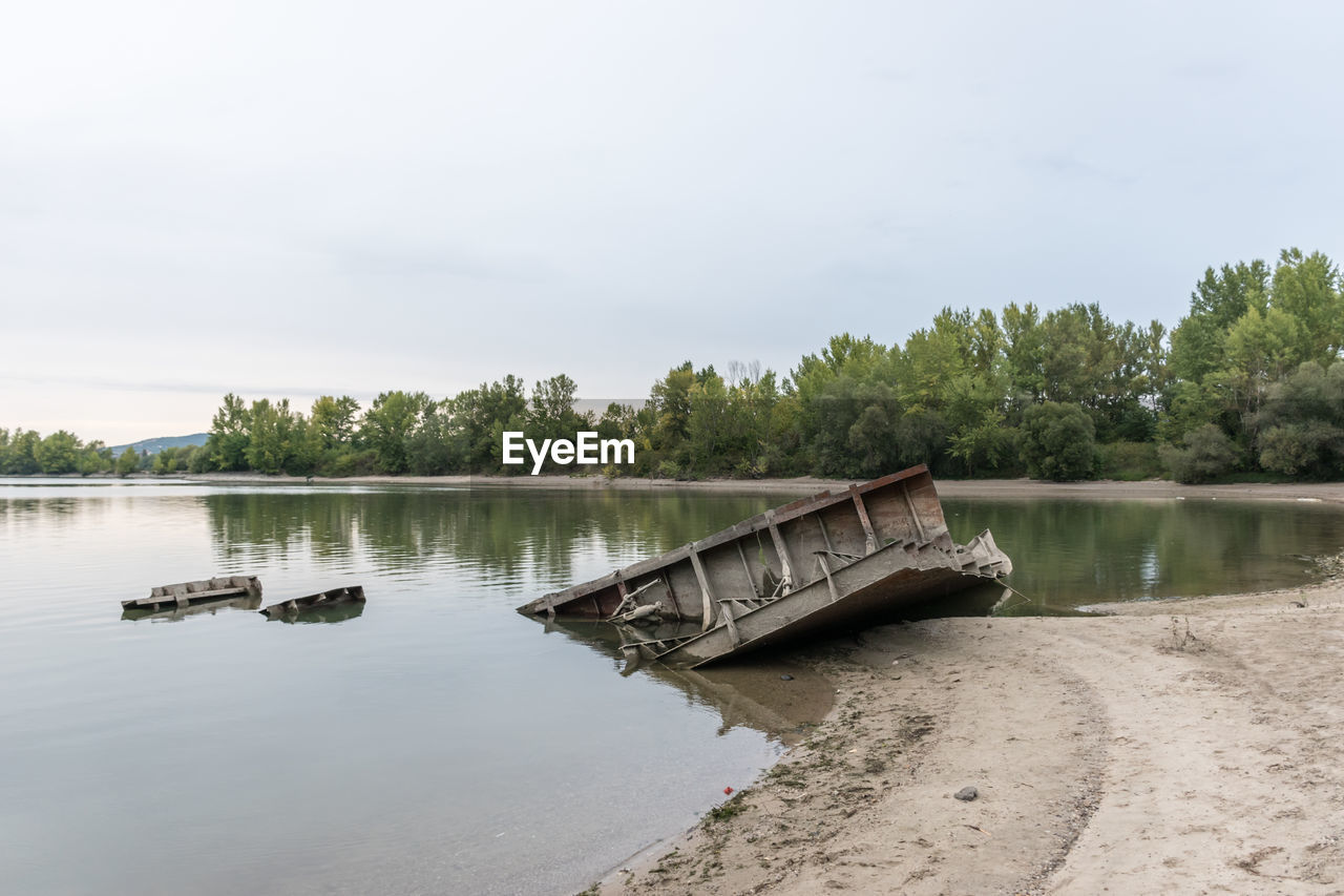 BOAT IN RIVER BY TREES AGAINST SKY