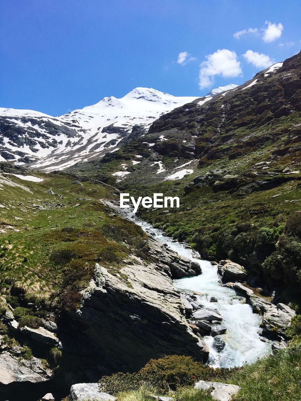 Scenic view of stream by mountains against sky