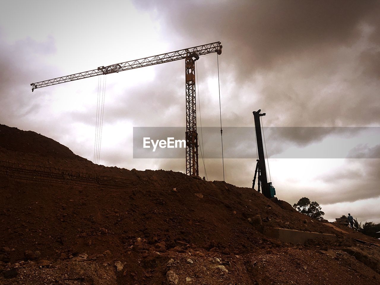 LOW ANGLE VIEW OF CRANES AT CONSTRUCTION SITE