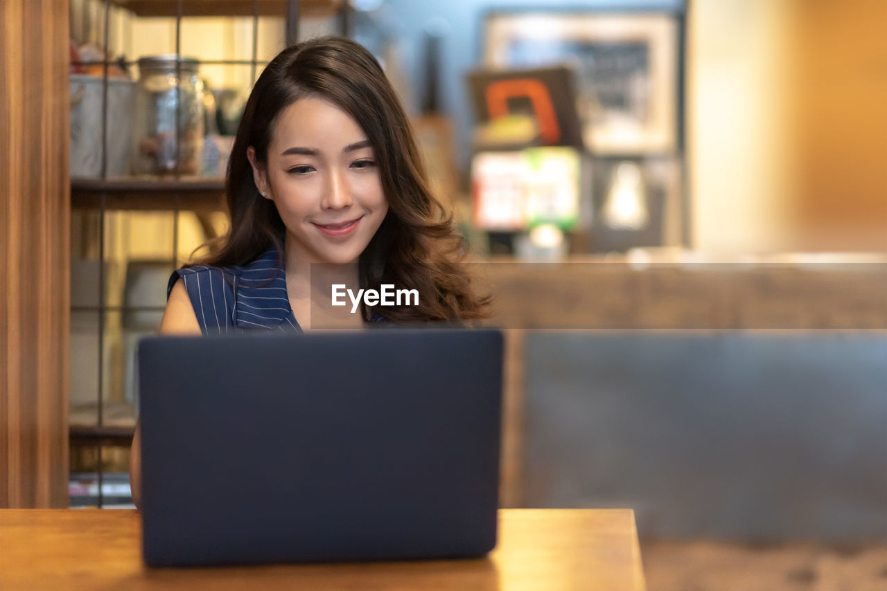 Businesswoman using laptop on table in cafe